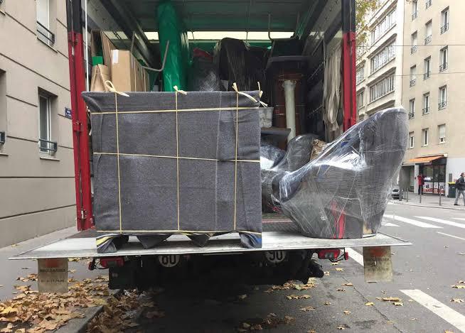 Canapé et fauteuil emballés chargés sur le hayon d'un camion OBR Transport à Paris
