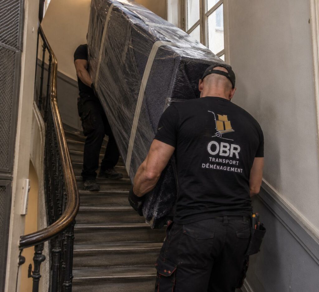 Deux déménageurs OBR Transport montant un matelas dans un escalier — intervention sans monte-meuble
